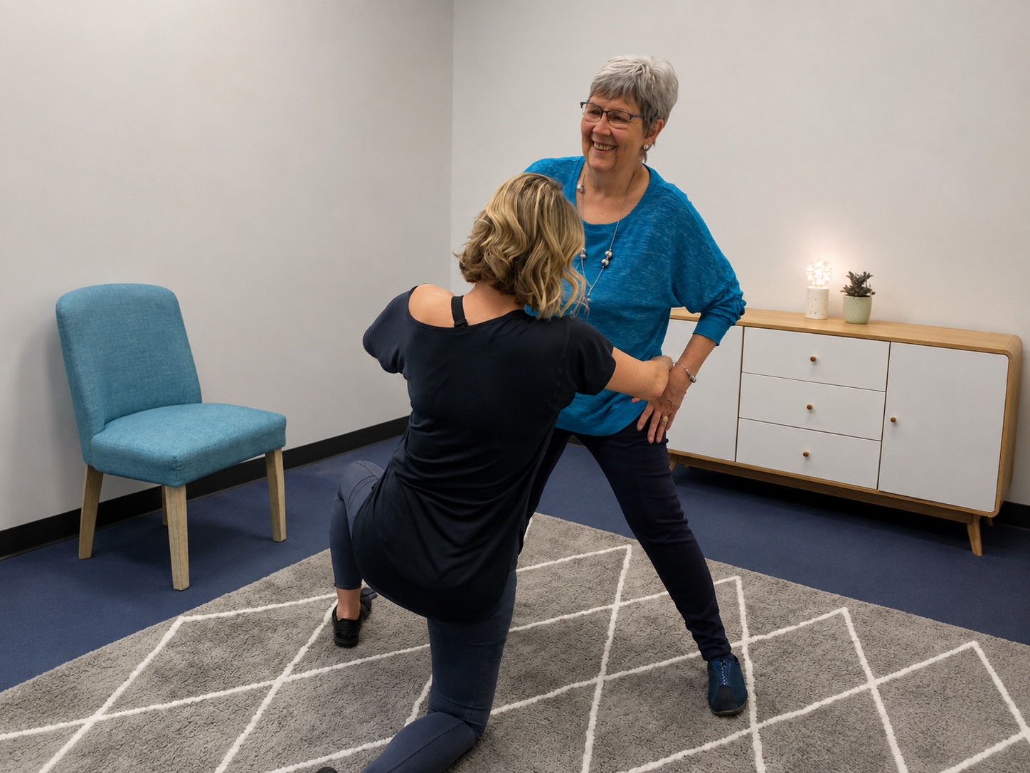 Trainer guiding an older client through a supported kneeling movement in the studio